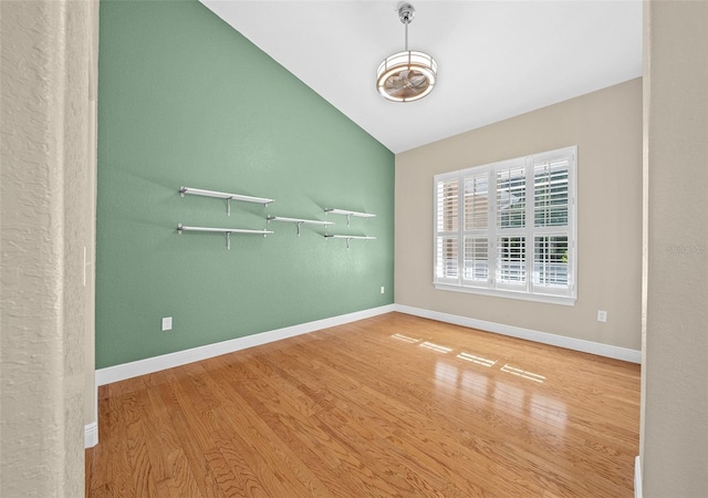 spare room featuring vaulted ceiling and hardwood / wood-style floors