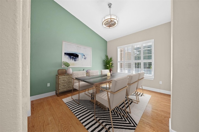 dining space featuring vaulted ceiling and light hardwood / wood-style flooring