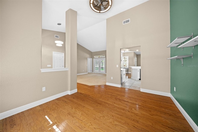 unfurnished living room featuring high vaulted ceiling and light hardwood / wood-style flooring