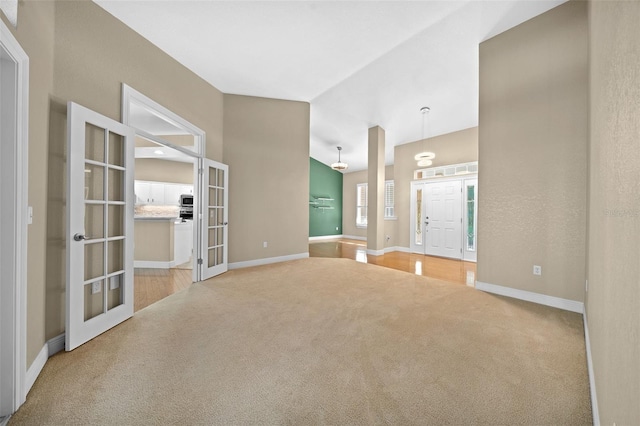 carpeted spare room featuring french doors and vaulted ceiling