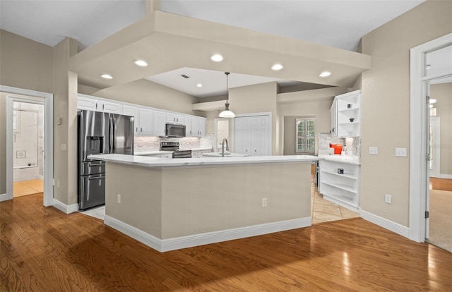 kitchen with decorative light fixtures, light hardwood / wood-style flooring, a center island with sink, stainless steel appliances, and white cabinets