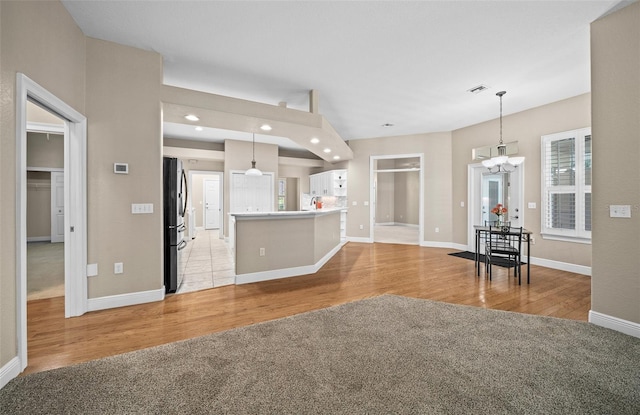 kitchen featuring fridge, pendant lighting, a notable chandelier, and light hardwood / wood-style flooring