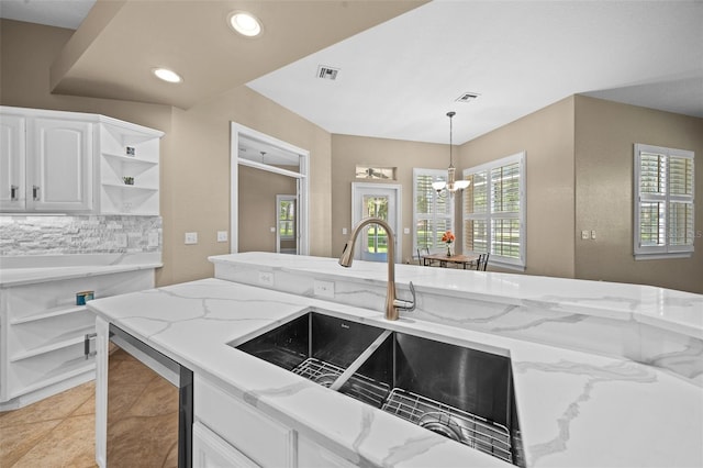 kitchen featuring decorative light fixtures, light stone countertops, sink, and white cabinets