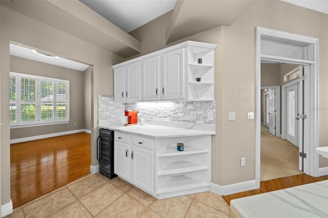 kitchen with white cabinetry, beverage cooler, decorative backsplash, and light hardwood / wood-style flooring