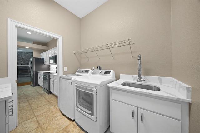 clothes washing area featuring independent washer and dryer, sink, and light tile patterned floors