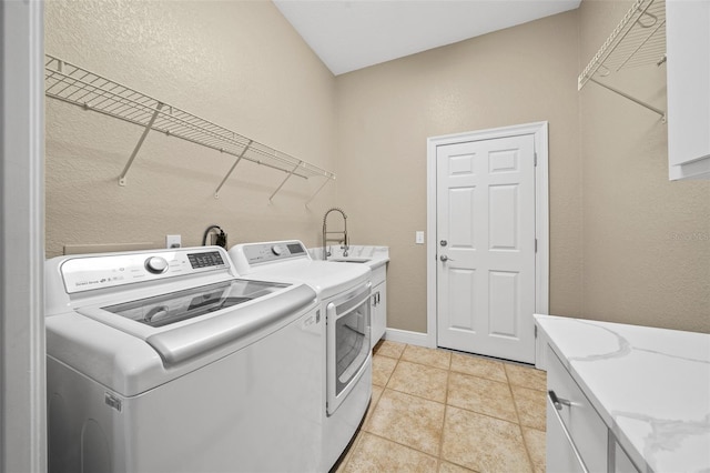 clothes washing area with cabinets, sink, washer and dryer, and light tile patterned floors