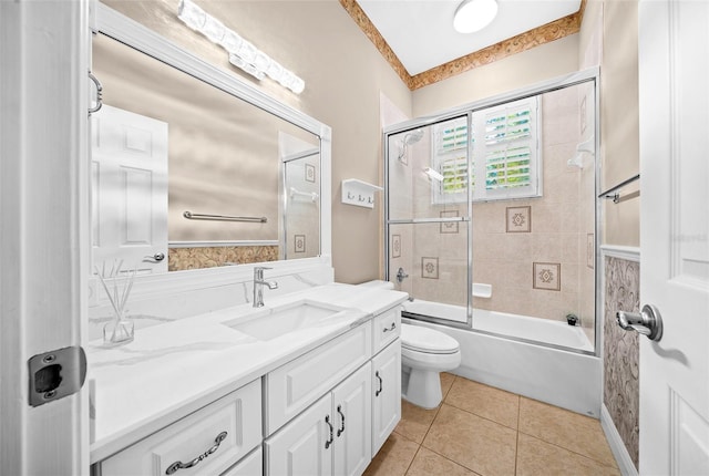 full bathroom featuring toilet, tile patterned floors, vanity, and bath / shower combo with glass door