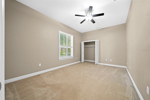 unfurnished bedroom featuring light carpet, a closet, and ceiling fan