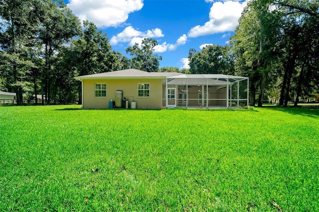 rear view of property with a yard and glass enclosure