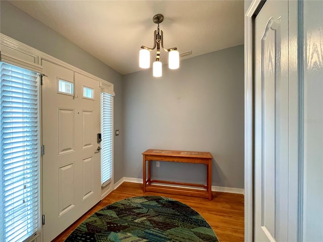 entrance foyer with wood-type flooring, a chandelier, and plenty of natural light