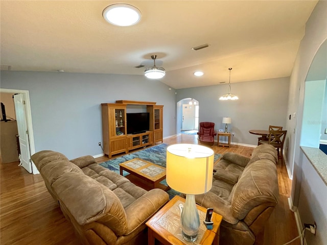 living room featuring lofted ceiling, an inviting chandelier, and hardwood / wood-style flooring