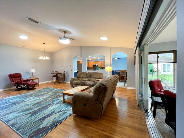 living room with wood-type flooring, vaulted ceiling, and a chandelier