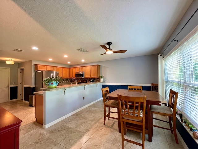 dining area with ceiling fan, a textured ceiling, and light tile patterned floors