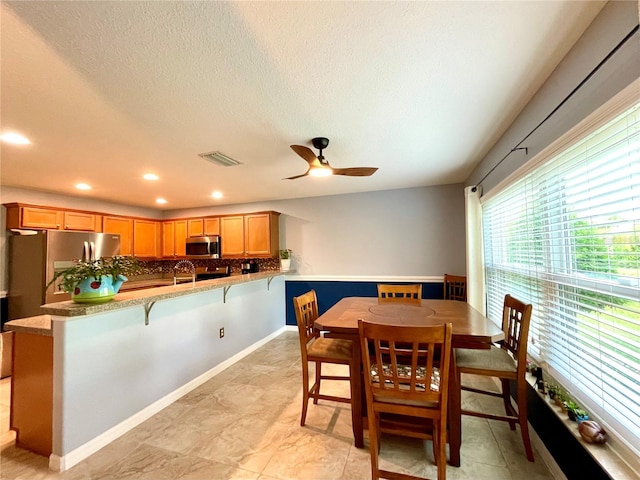 dining room featuring ceiling fan, a textured ceiling, and light tile patterned floors