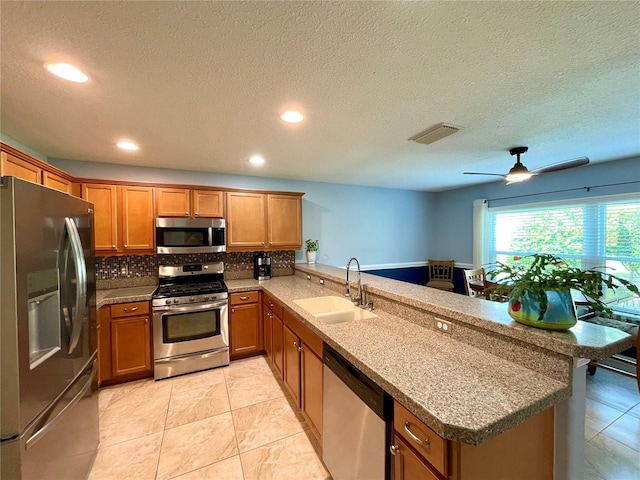 kitchen featuring ceiling fan, kitchen peninsula, light tile patterned floors, stainless steel appliances, and sink