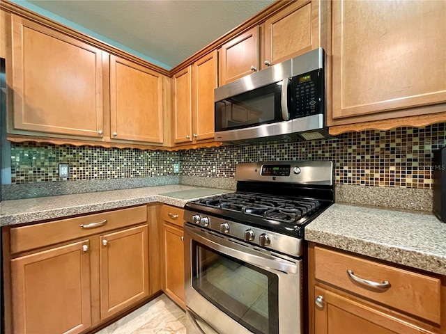 kitchen with light tile patterned flooring, appliances with stainless steel finishes, and backsplash