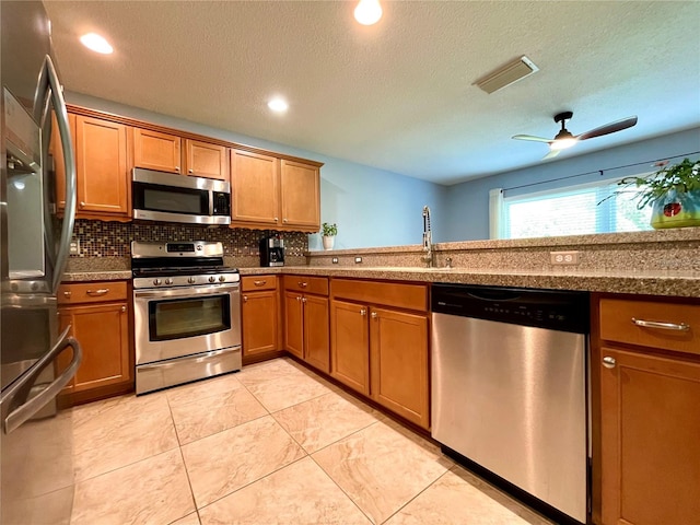 kitchen featuring ceiling fan, light tile patterned flooring, stainless steel appliances, and a textured ceiling