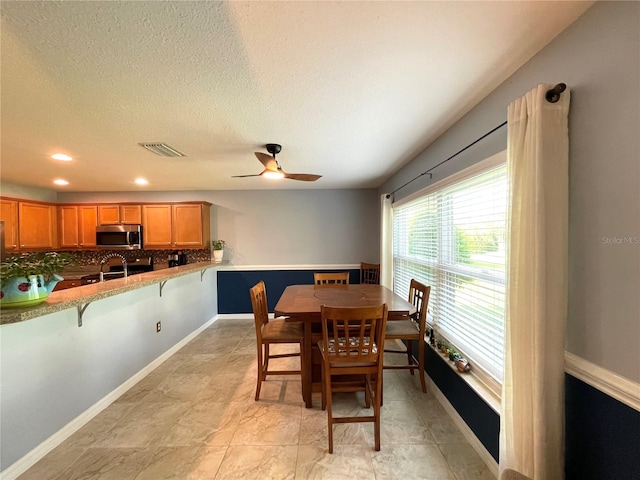 dining room featuring ceiling fan, light tile patterned flooring, and a textured ceiling