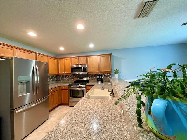 kitchen with stainless steel appliances, a textured ceiling, decorative backsplash, sink, and kitchen peninsula