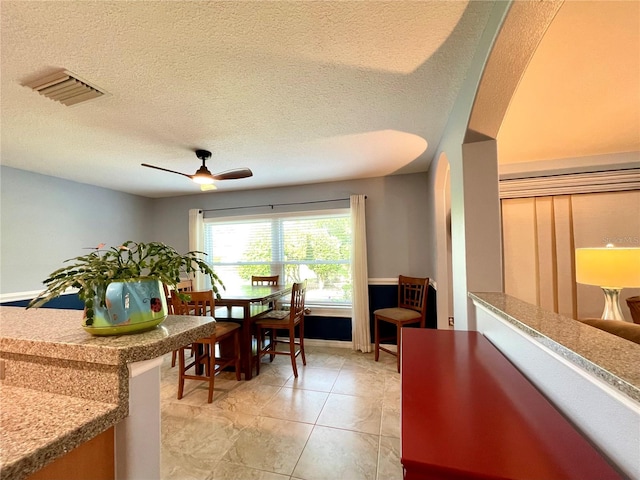 tiled dining area featuring ceiling fan and a textured ceiling