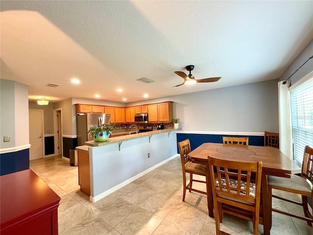 tiled dining area with a textured ceiling and ceiling fan