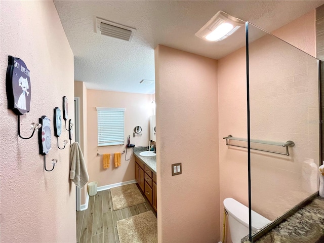 bathroom featuring vanity, wood-type flooring, a textured ceiling, and toilet