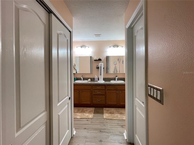 bathroom with wood-type flooring, a textured ceiling, and double vanity