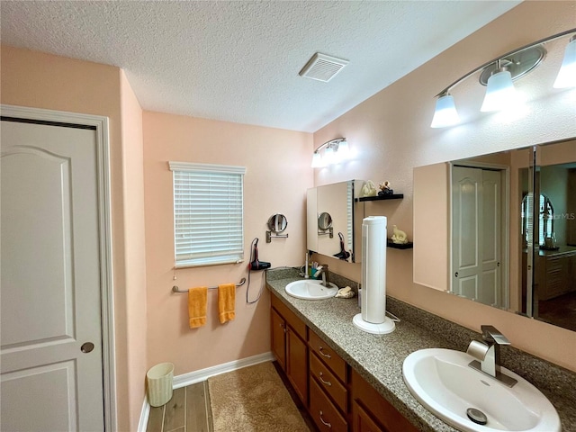 bathroom with dual bowl vanity and a textured ceiling