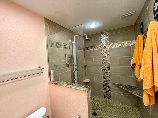 bathroom with a shower with shower door, a textured ceiling, and toilet