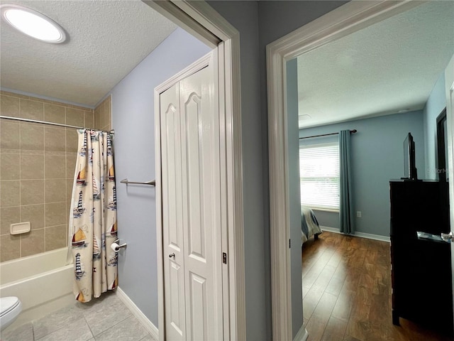 bathroom featuring shower / tub combo with curtain, a textured ceiling, toilet, and hardwood / wood-style flooring