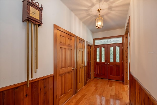 entryway featuring a wainscoted wall, wood walls, and light wood-type flooring