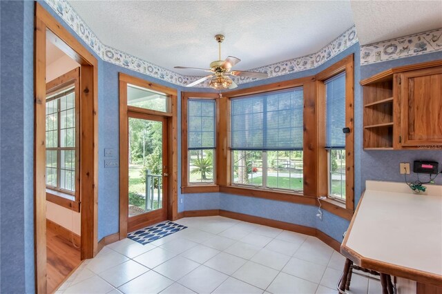 doorway featuring a textured ceiling, ceiling fan, and light tile patterned floors