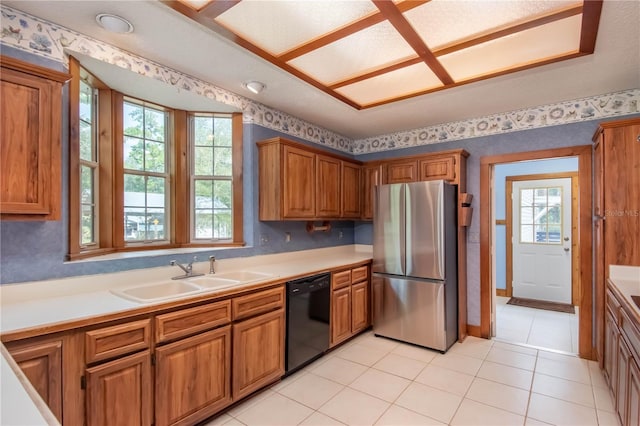 kitchen with a sink, brown cabinets, black dishwasher, and freestanding refrigerator