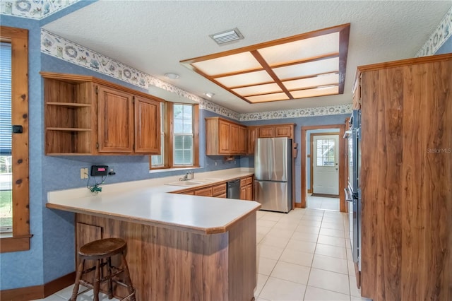 kitchen with kitchen peninsula, stainless steel fridge, light tile patterned flooring, and dishwasher