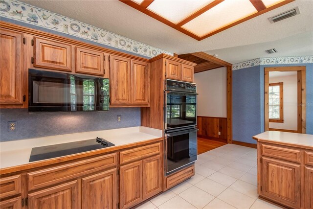 kitchen with light tile patterned floors, a textured ceiling, and black appliances