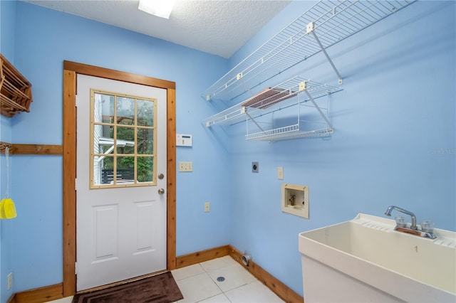 laundry room featuring hookup for a washing machine, hookup for an electric dryer, light tile patterned floors, sink, and a textured ceiling