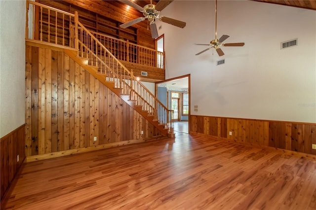 interior space with hardwood / wood-style flooring, high vaulted ceiling, wood walls, and ceiling fan