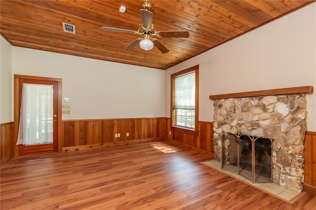 unfurnished living room featuring wood finished floors, a wainscoted wall, visible vents, a fireplace, and wooden ceiling