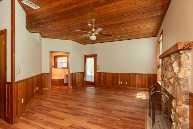 unfurnished living room featuring ceiling fan, hardwood / wood-style flooring, wooden ceiling, and a stone fireplace