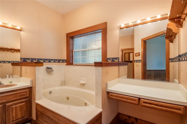 bathroom featuring wallpapered walls, vanity, a tub with jets, and wainscoting