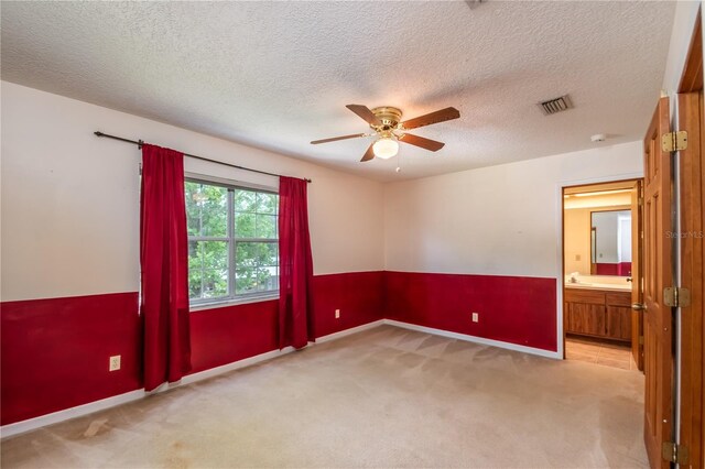 empty room with a textured ceiling, ceiling fan, and light colored carpet