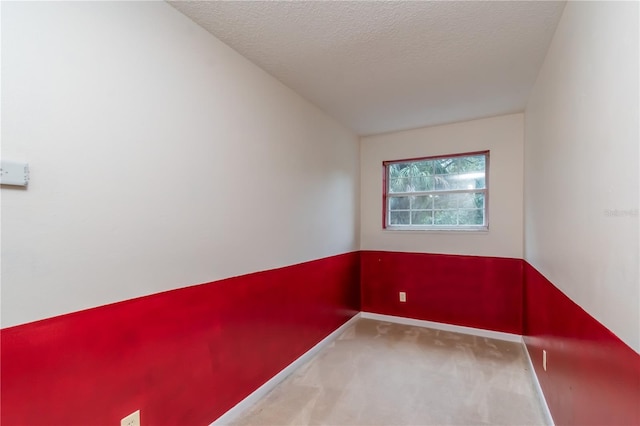 carpeted spare room featuring a textured ceiling and baseboards