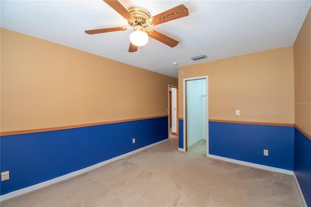 spare room featuring ceiling fan, a textured ceiling, and light colored carpet