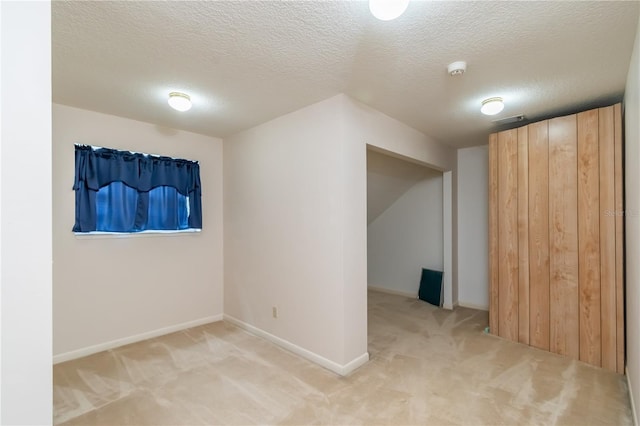 additional living space featuring baseboards, light carpet, a textured ceiling, and visible vents