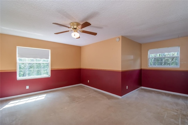 unfurnished room with a wealth of natural light, carpet floors, ceiling fan, and a textured ceiling