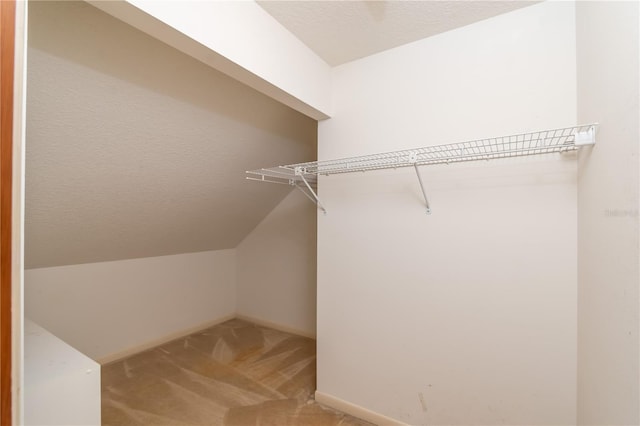 walk in closet featuring vaulted ceiling and carpet floors