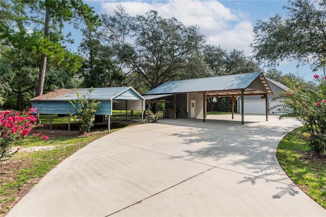 view of front of property featuring a garage, a carport, and an outdoor structure