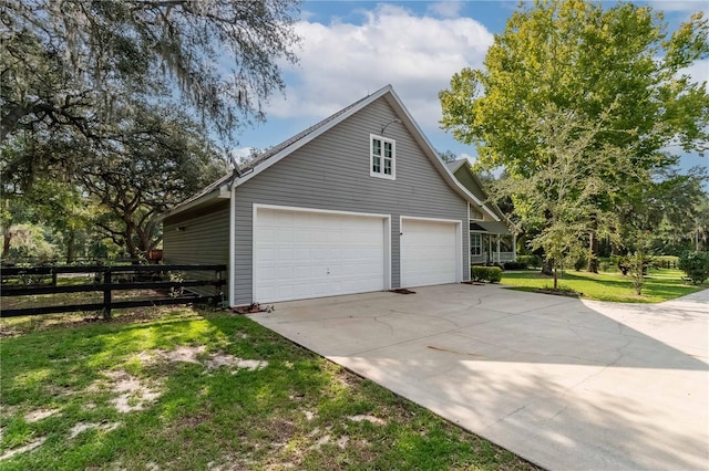 view of side of home with a garage, a lawn, concrete driveway, and fence