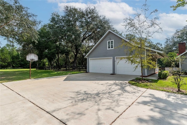 view of property exterior featuring a lawn, concrete driveway, a garage, and fence