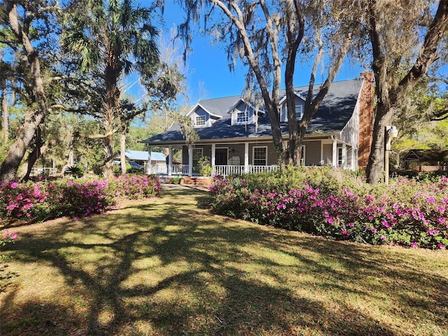 rear view of property featuring a yard and covered porch